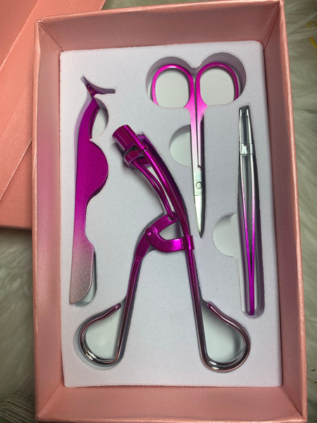 Pink tool kit with tweezers, scissors, applicator, and curler.